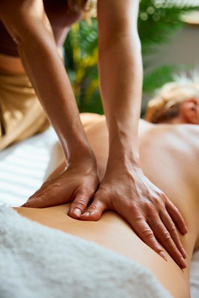 Massage therapist hands on client back in spa setting